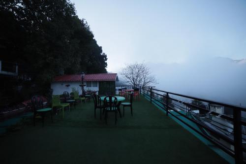 a deck with tables and chairs next to a fence at Aman The Lake Side Nainital in Nainital