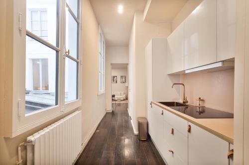 une cuisine avec des armoires blanches et une fenêtre dans l'établissement Magnifique Appartement au Cœur du Marais, à Paris