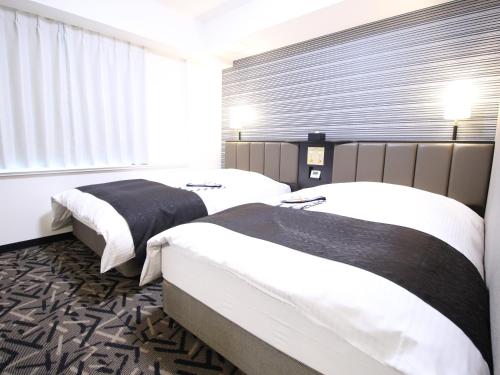 a hotel room with two beds and a window at APA Hotel Hikoneminami in Hikone