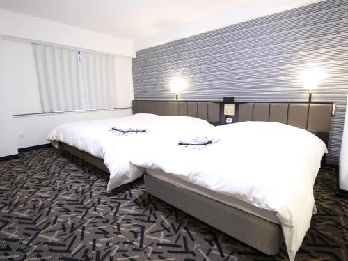 a hotel room with two beds and a window at APA Hotel Hikoneminami in Hikone
