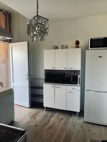 a kitchen with white cabinets and a black microwave at Appartement avec terrasse privative in Celles-sur-Plaine