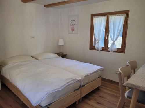 a bedroom with a bed with white sheets and a window at Osteria Anzonico in Anzonico
