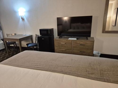 a hotel room with a bed and a flat screen tv at Abilene Whitten Inn in Abilene