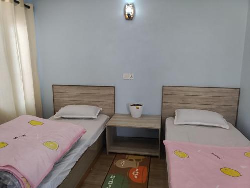 two beds in a small room with a table and a bedskirts at Family Home in Pātan