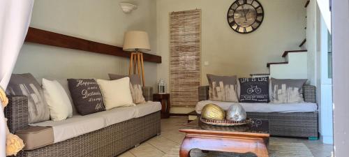 a living room with a couch and a clock on the wall at Le Morne View Duplex in Rivière Noire