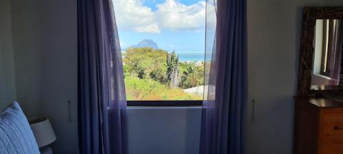 a window in a bedroom with a view of the ocean at Le Morne View Duplex in Rivière Noire