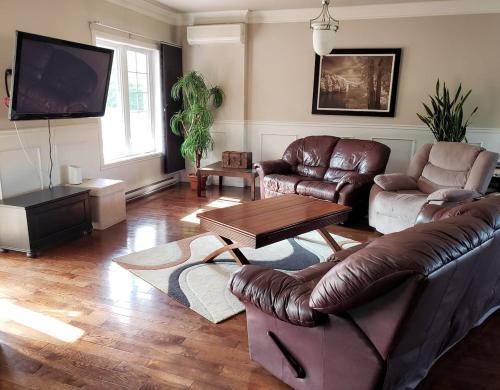 a living room with a leather couch and a table at La campagne en ville avec spa in Laval