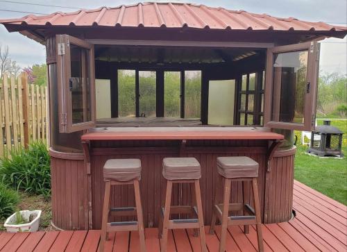 a bar on a deck with stools around it at La campagne en ville avec spa in Laval