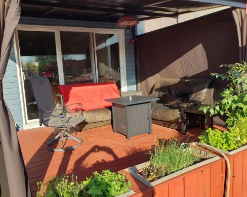 a patio with a couch and a table on a deck at La campagne en ville avec spa in Laval