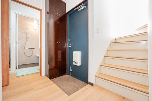 a bathroom with a blue door and stairs with a shower at Akabanestay A 志茂 in Tokyo