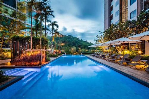 Sea View High Flr,2 Bed Room Exclusive At Pattaya في جنوب باتايا: حمام سباحة في فندق مع كراسي ومظلات