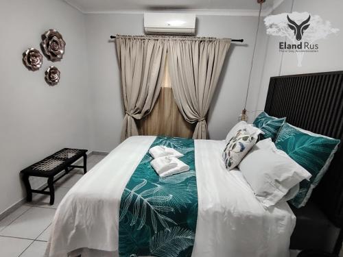 a bedroom with a bed with a green and white blanket at Eland Rus Micro Stay Self Catering in Kathu