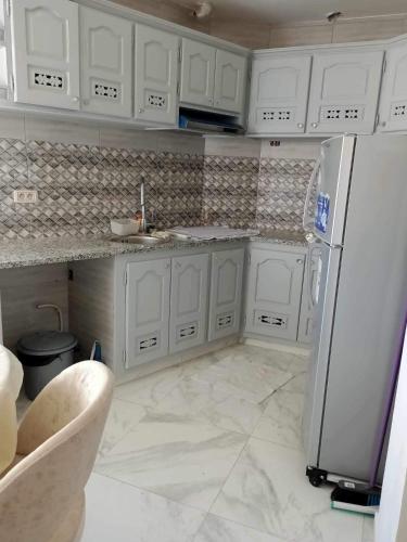a kitchen with white cabinets and a refrigerator at Dar hana in Rafrāf