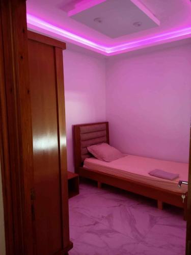 a room with a bed with pink lights on the ceiling at Dar hana in Rafrāf