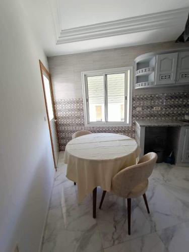 a white room with a table and a fireplace at Dar hana in Rafrāf