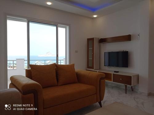 a living room with a couch and a flat screen tv at Dar hana in Rafrāf