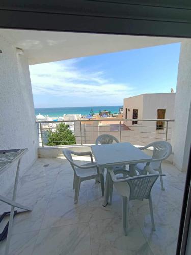 a table and chairs on a balcony with a view of the ocean at Dar hana in Rafrāf