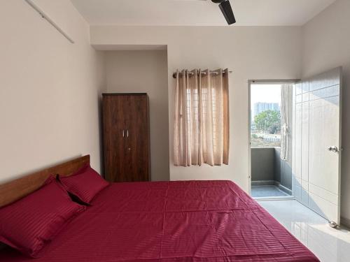 a bedroom with a red bed and a large window at 1Bhk in Hennur 1st floor near Bhartiya city 101 in Bengaluru