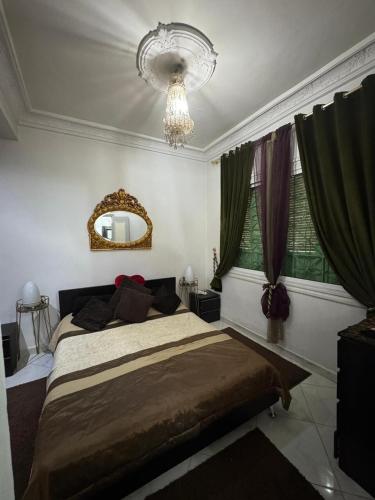 a bedroom with a large bed and a chandelier at Appartement Confort & Proximité in Meknès