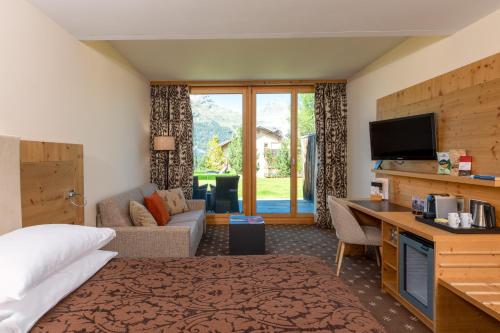 a hotel room with a bed and a desk and a tv at Nira Alpina in Silvaplana