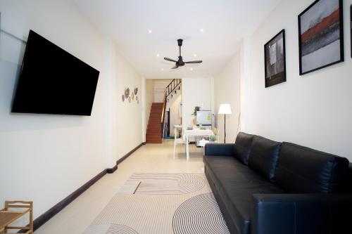 a living room with a black couch and a flat screen tv at OH Homes - Samsen 10 in Bangkok