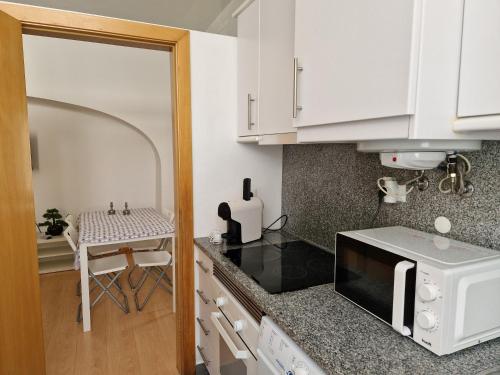 a kitchen with white cabinets and a white microwave at Casa das Amas do Cardeal in Évora