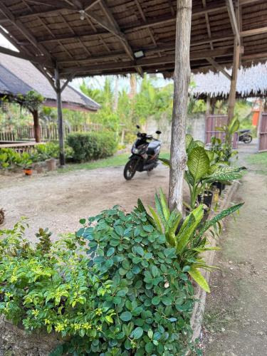 a motorcycle parked under a building next to a green bush at Cecilia's Garden Guesthouse in Siquijor