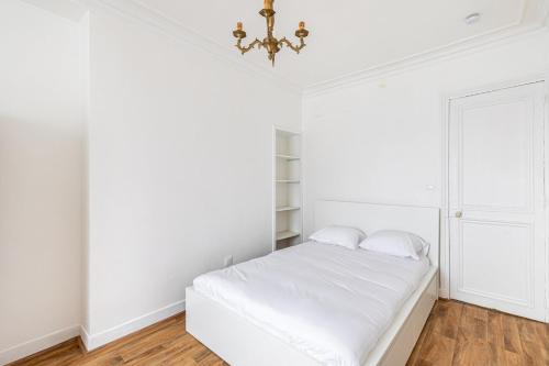 - une chambre blanche avec un lit et un lustre dans l'établissement GuestReady - Comfortable Nest in La Chapelle, à Paris