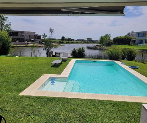 ein Pool im Gras neben einem Wasserkörper in der Unterkunft Casa a la laguna in Belén de Escobar