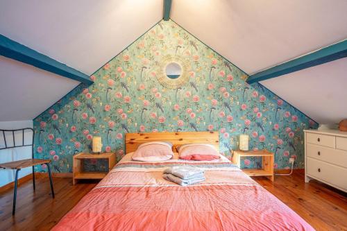- une chambre avec un grand lit et du papier peint floral dans l'établissement Les Cailloux Verts, à Étretat