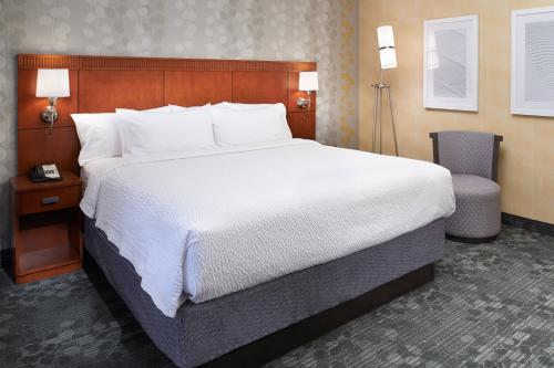 a hotel room with a large bed and a chair at Courtyard by Marriott Detroit Livonia in Livonia
