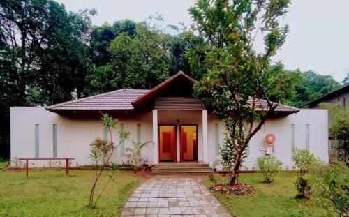 a small white house with a red door at Abad Brookside Wayanad in Vythiri
