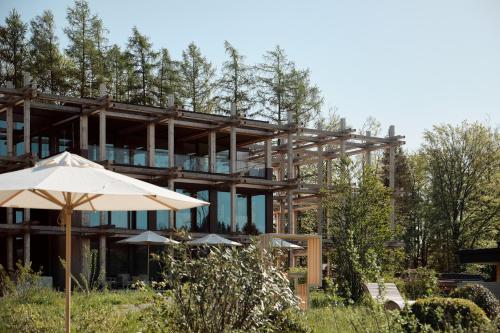 a building with an umbrella and some trees at Hotel BERGEBLICK in Bad Tölz