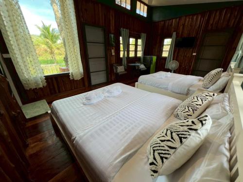 a bedroom with two beds and a window at Coco farm stay Suanphueng in Ratchaburi