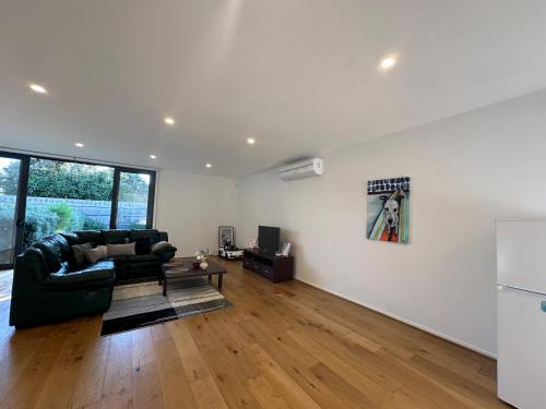a living room with a black couch and a refrigerator at 89B - Your Dream Stay Business or Travel Mornings with coffee in Bentleigh in Heatherton