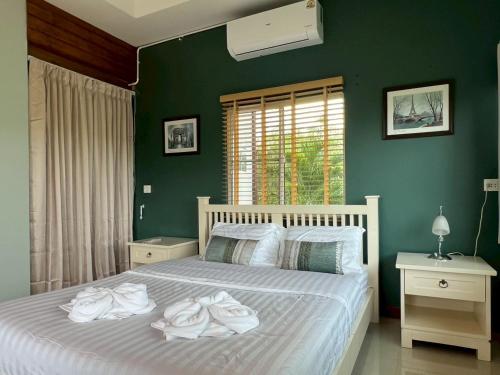 a bedroom with a white bed with green walls at Coco farm stay Suanphueng in Ratchaburi