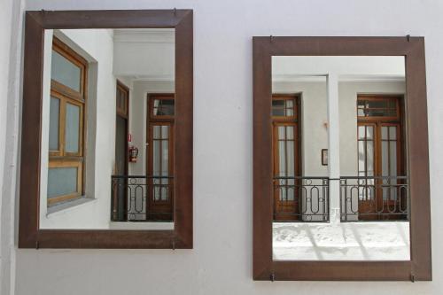 a mirror on a wall with three windows at A Hotel in Buenos Aires