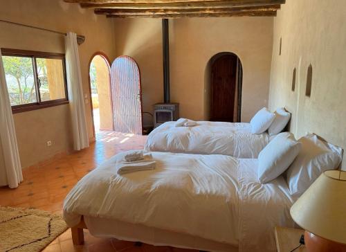 a bedroom with two white beds and a fireplace at Les Jardins de la Santé in Tamazouzte