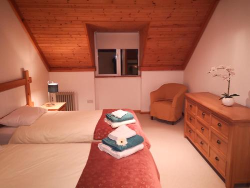 a bedroom with two beds and a dresser and a chair at 4 bedroomed house in Waterville close to the beach in Waterville