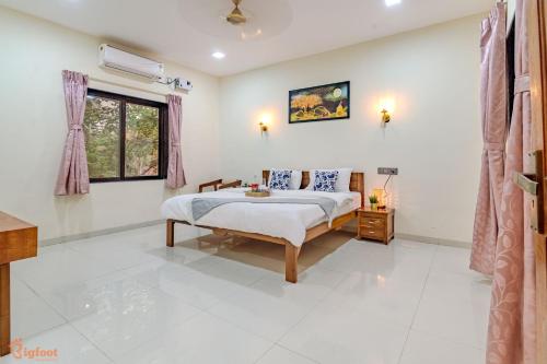 a white bedroom with a bed and a window at Islander Retreat Alibaug in Alibag