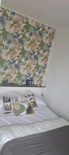 - un lit avec une tête de lit fleurie et des oreillers dans l'établissement Orienté Nord frais bien ventilé grand studio balcon wifi parking vue étage supérieur, à Amélie-les-Bains-Palalda