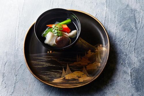 a black plate with a bowl of food on a table at The Ritz-Carlton Kyoto in Kyoto