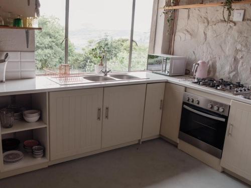a kitchen with white cabinets and a sink and a window at Riverbed Africa in Lydenburg