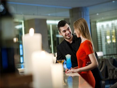 a man and a woman standing next to a bar at The Sebel Xining-Managed By Sofitel in Xining