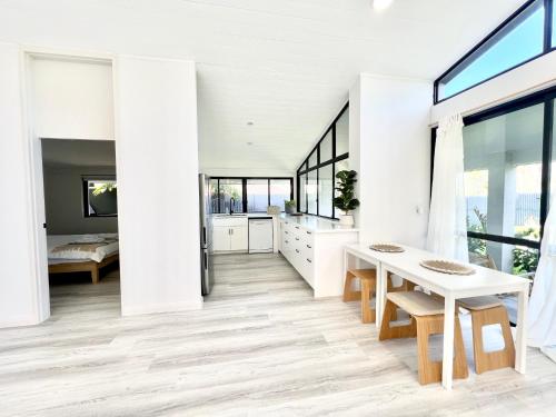 a white kitchen with a table and a bed at Amazing Ocean Villa close to Natural Rock Pools in Sydney