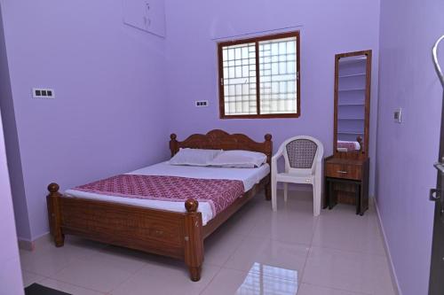a bedroom with a bed and a chair and a window at Kavitha Family Home stay TVM in Tiruvannāmalai
