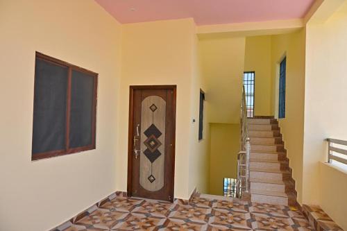 a hallway with a wooden door and stairs at Kavitha Family Home stay TVM in Tiruvannāmalai