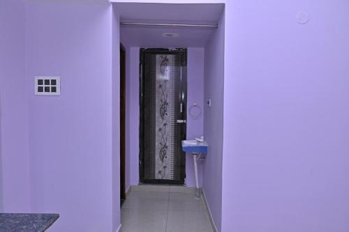 a hallway with a door to a bathroom with purple walls at Kavitha Family Home stay TVM in Tiruvannāmalai