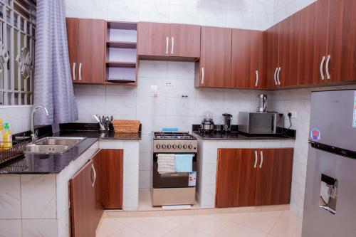 a kitchen with wooden cabinets and a stove top oven at Spacious & Quiet 2BR Apt with Wi-Fi Buwate Mall in Buwate