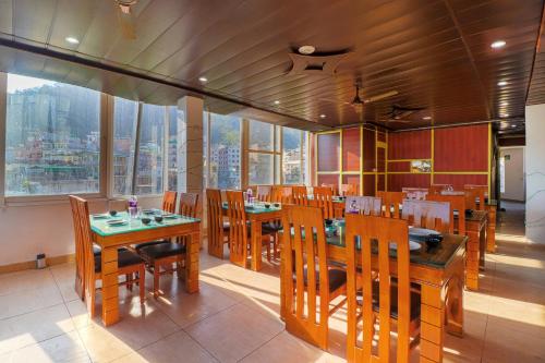 un ristorante con tavoli e sedie in legno e una grande finestra di Divine Dev Darshan Valley a Rishikesh